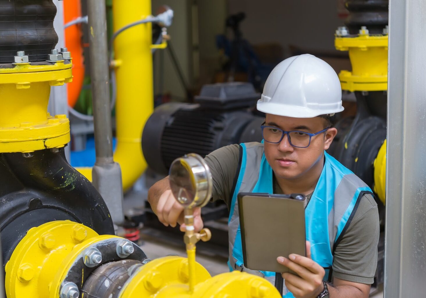 Asian engineer wearing glasses working in the boiler room,maintenance checking technical data of heating system equipment,Thailand people